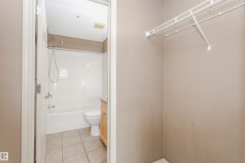 Bathroom with a white tub and shower combination, chrome fixtures, a light wood-finish vanity, and tiled flooring - 1-402 4245 139 Avenue, Edmonton, AB - Indoor Photo Showing Bathroom