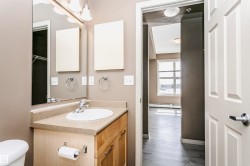 Bathroom vanity featuring a light wood-finish cabinet with silver hardware, an integrated sink, and a light-toned countertop - 