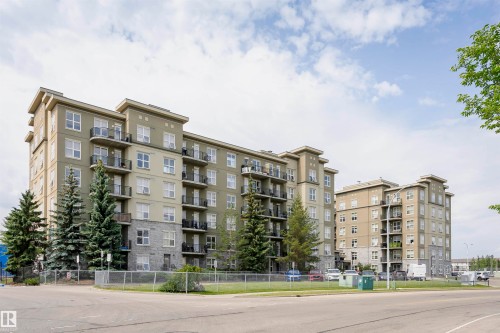 Multi-story residential buildings featuring varied facade treatments including stone accents, stucco, and prominent balconies with metal railings - 1-402 4245 139 Avenue, Edmonton, AB - Outdoor With Balcony With Facade