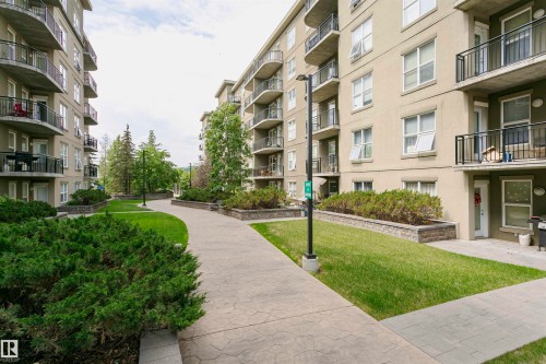 Landscaped courtyard featuring a patterned concrete pathway, manicured lawns, mature trees, and shrubbery - 1-402 4245 139 Avenue, Edmonton, AB - Outdoor With Balcony
