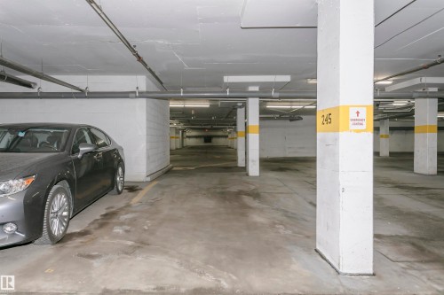 Underground parking facility with concrete flooring, exposed overhead piping, and fluorescent lighting fixtures - 1-402 4245 139 Avenue, Edmonton, AB - Indoor Photo Showing Garage