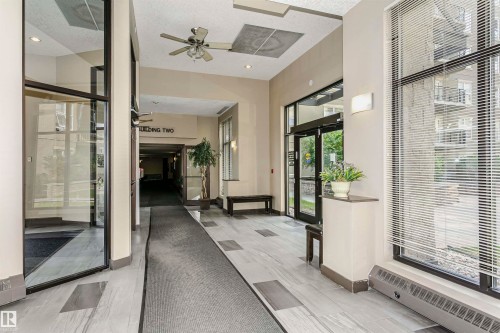 Lobby area featuring large format tile flooring, a ceiling fan, and extensive window-side venetian blinds - 1-402 4245 139 Avenue, Edmonton, AB - Indoor Photo Showing Other Room