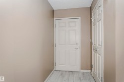 Entryway featuring light wood-finish flooring, neutral-toned walls, a white paneled door, and a white paneled closet door with silver-tone hardware - 