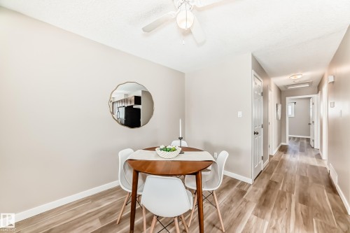 The property features wood-look flooring throughout, a neutral color palette on the walls, and a ceiling fan with integrated lighting - 10327 150 Street, Edmonton, AB - Indoor Photo Showing Dining Room