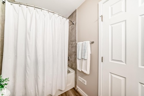 This bathroom features a shower/tub combination with a white shower curtain and tiled surround - 10327 150 Street, Edmonton, AB - Indoor