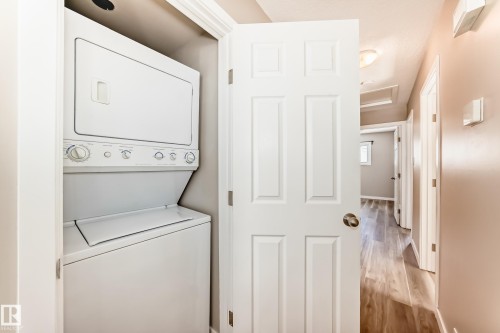 The property includes a stacked washer and dryer unit, set within a dedicated alcove with a white door - 10327 150 Street, Edmonton, AB - Indoor Photo Showing Laundry Room