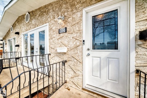The property features an entryway with a white paneled door, a decorative glass insert, and an exterior light fixture - 10327 150 Street, Edmonton, AB - Outdoor With Exterior