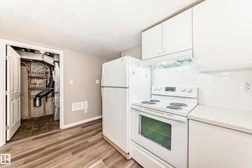 The kitchen features white cabinetry, white appliances, and a white subway tile backsplash - 10327 150 Street, Edmonton, AB - Indoor Photo Showing Kitchen