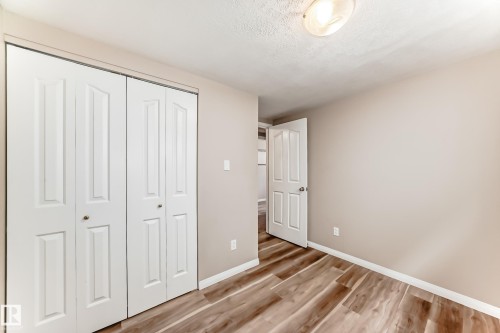 This room features hardwood style flooring, a neutral wall color, and white bi-fold closet doors - 10327 150 Street, Edmonton, AB - Indoor Photo Showing Other Room