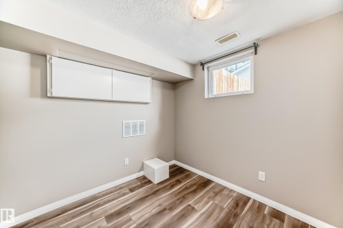 Room featuring wood-look flooring, light-colored walls, and a window providing natural light - 10327 150 Street, Edmonton, AB - Indoor Photo Showing Other Room