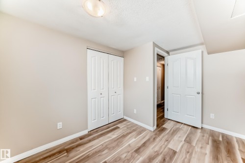 Room with light wood-style flooring, a closet with bi-fold doors, and a white paneled door - 10327 150 Street, Edmonton, AB - Indoor Photo Showing Other Room