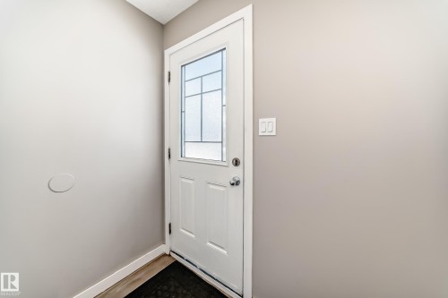 Entryway features a white door with decorative glass inserts, a light switch, and light-colored walls - 10327 150 Street, Edmonton, AB - Indoor Photo Showing Other Room