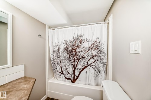 This bathroom features a shower-over-tub combination, a vanity with a countertop, and a mirror - 10327 150 Street, Edmonton, AB - Indoor Photo Showing Bathroom