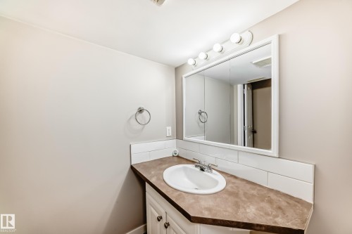 Bathroom vanity with an integrated sink, a large wall-mounted mirror, and overhead lighting - 10327 150 Street, Edmonton, AB - Indoor Photo Showing Bathroom