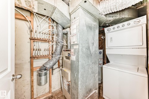 Utility area featuring a white stacked washer and dryer, a water heater, and a furnace - 10327 150 Street, Edmonton, AB - Indoor Photo Showing Laundry Room