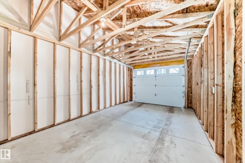 The property features a garage with exposed wooden beams, a concrete floor, and a white garage door with upper window panels - 10327 150 Street, Edmonton, AB - Indoor Photo Showing Garage