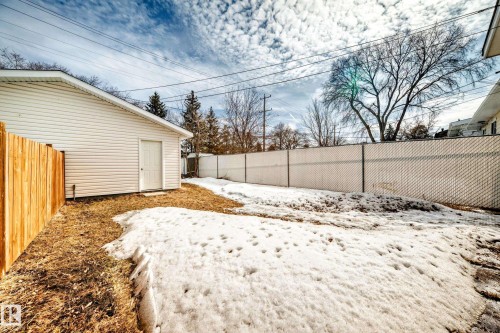 The property features a detached building with white siding, alongside a wooden fence, and a chain link fence - 10327 150 Street, Edmonton, AB - Outdoor