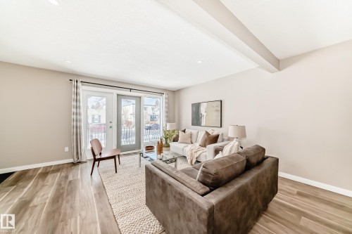 Living area featuring hardwood flooring, light-colored walls, a ceiling beam, recessed lighting, and a glass-paneled door - 10327 150 Street, Edmonton, AB - Indoor Photo Showing Other Room