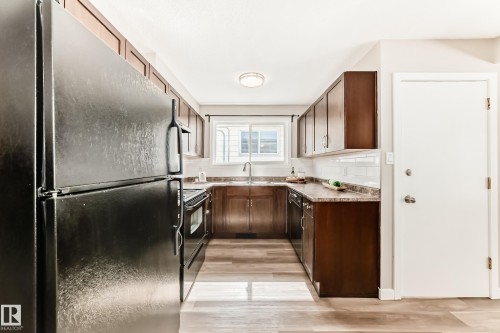 The kitchen features wood cabinets, a white subway tile backsplash, and light-colored countertops - 10327 150 Street, Edmonton, AB - Indoor Photo Showing Kitchen