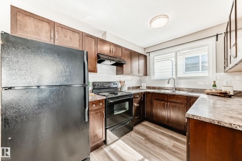 The kitchen features rich wood cabinetry, a subway tile backsplash, and a window above the double sink - 10327 150 Street, Edmonton, AB - Indoor Photo Showing Kitchen