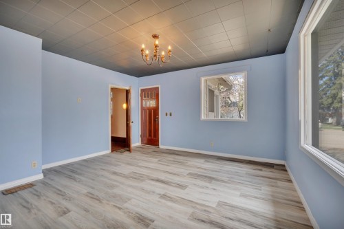 Spacious room featuring light wood-finish flooring, a contemporary ceiling, and a prominent window - 4907 48 Avenue, Leduc, AB - Indoor Photo Showing Other Room