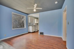Spacious interior with wood-finish flooring, a large picture window, and a ceiling fan - 