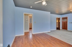 Interior space featuring a mix of wood-finish flooring and light-toned plank flooring, light blue wall finishes, and a gray acoustic tile ceiling with an attached ceiling fan - 
