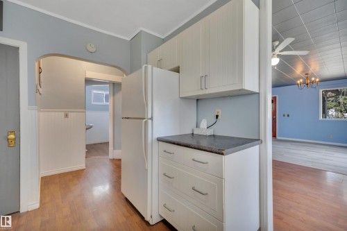 Kitchen area featuring wood-finish flooring, white cabinetry, and a dark countertop - 4907 48 Avenue, Leduc, AB - Indoor Photo Showing Kitchen