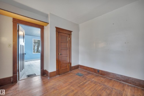 Warm wood-finish flooring complemented by substantial wood trim and baseboards - 4907 48 Avenue, Leduc, AB - Indoor Photo Showing Other Room