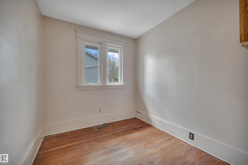 Room featuring wood-finish flooring, light-toned walls, and a double window with white trim - 4907 48 Avenue, Leduc, AB - Indoor Photo Showing Other Room