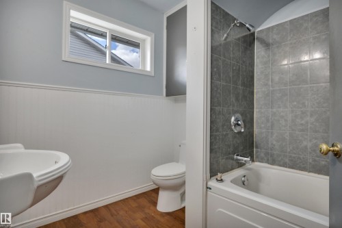 Bathroom featuring a white pedestal sink, toilet, and a bathtub with a tiled shower surround - 4907 48 Avenue, Leduc, AB - Indoor Photo Showing Bathroom