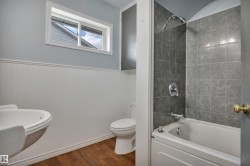 Bathroom featuring a white pedestal sink, toilet, and a bathtub with a tiled shower surround - 
