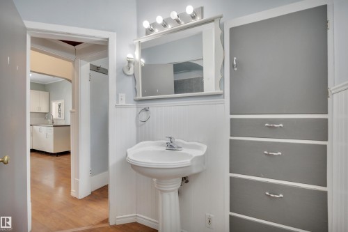 Pedestal sink with chrome faucet, wall-mounted mirror, and vanity lighting - 4907 48 Avenue, Leduc, AB - Indoor Photo Showing Bathroom