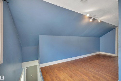 Attic space featuring wood-finish flooring, track lighting, and a sloped ceiling - 4907 48 Avenue, Leduc, AB - Indoor Photo Showing Other Room