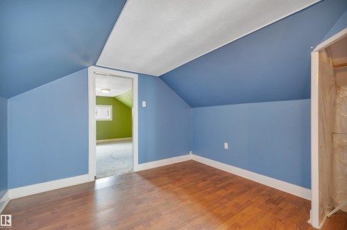 Attic space featuring wood-finish flooring, blue painted walls, and a white sloped ceiling - 4907 48 Avenue, Leduc, AB - Indoor Photo Showing Other Room