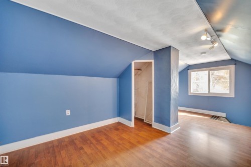 Attic space featuring wood-finish flooring, a window providing natural illumination, and an exposed closet area - 4907 48 Avenue, Leduc, AB - Indoor Photo Showing Other Room