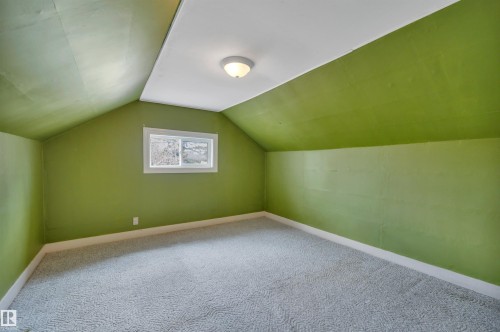 Room featuring sloped ceilings, a single pane window, wall-mounted light fixture, and patterned carpet flooring - 4907 48 Avenue, Leduc, AB - Indoor Photo Showing Other Room