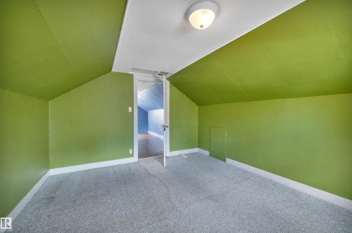 Attic space with sloped ceilings, a flush mount ceiling light, and an access panel - 4907 48 Avenue, Leduc, AB - Indoor