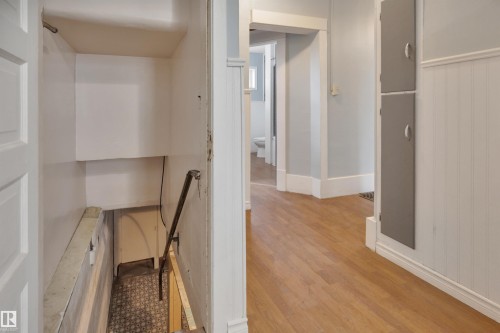 Hardwood-finish flooring extending through the hallway, white beadboard paneling, and built-in storage cabinets - 4907 48 Avenue, Leduc, AB - Indoor Photo Showing Other Room