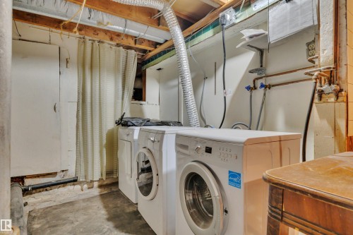 Dedicated laundry area with exposed wood ceiling joists and concrete flooring - 4907 48 Avenue, Leduc, AB - Indoor Photo Showing Laundry Room