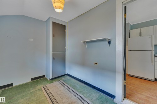 Interior space featuring a built-in double cabinet, a wall-mounted shelf, and an overhead light fixture - 4907 48 Avenue, Leduc, AB - Indoor Photo Showing Other Room