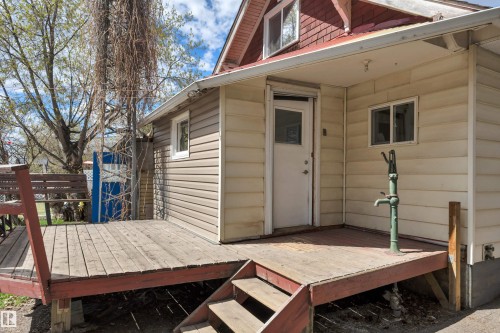 Exterior featuring light-colored vinyl siding, a red shingle roof, and multiple windows - 4907 48 Avenue, Leduc, AB - Outdoor With Exterior
