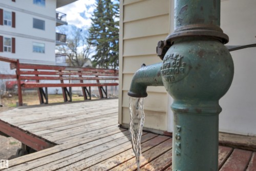 Vintage-style water pump with flowing water on a wood-plank deck - 4907 48 Avenue, Leduc, AB - Outdoor With Exterior