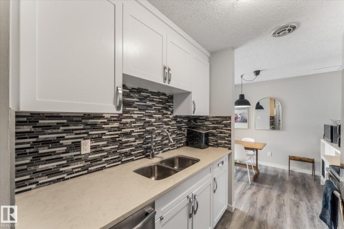 Kitchen featuring white shaker-style cabinetry, a dual-basin stainless steel sink, a modern tile backsplash, and light-toned countertops - 35 Mcleod Place, Edmonton, AB - Indoor Photo Showing Kitchen With Double Sink