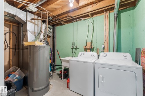 Basement utility area featuring a water heater, furnace, exposed ceiling joists, and laundry hookups with a washer and dryer - 35 Mcleod Place, Edmonton, AB - Indoor Photo Showing Laundry Room