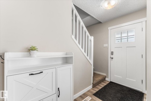 Entryway featuring a white paneled door with glass inserts, wood-finish flooring, a carpeted staircase with white railings, and neutral wall paint - 35 Mcleod Place, Edmonton, AB - Indoor Photo Showing Other Room
