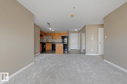 Open-concept living area featuring light gray carpeting and neutral wall tones - 