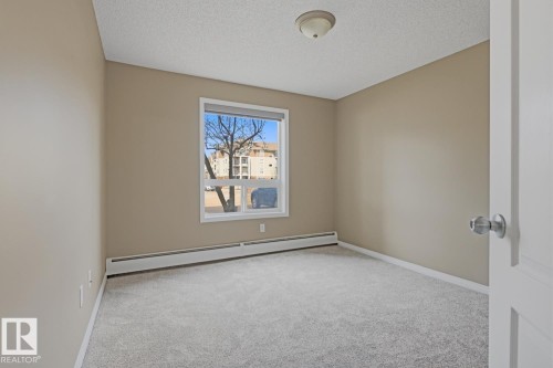Neutral-toned interior room featuring light gray carpeting and baseboard trim - 5106 7335 South Terwillegar Drive, Edmonton, AB - Indoor Photo Showing Other Room