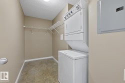 Dedicated laundry area featuring a white stacked washer and dryer, tile flooring, and integrated wire shelving - 