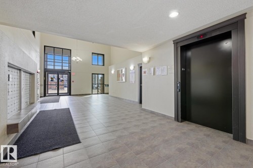 Spacious common area featuring large format tile flooring, a prominent elevator, and a wall of individual mailboxes - 5106 7335 South Terwillegar Drive, Edmonton, AB - Indoor Photo Showing Other Room